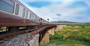Train Al Andalus traversant un pont ferroviaire dans la campagne andalouse avec collines verdoyantes