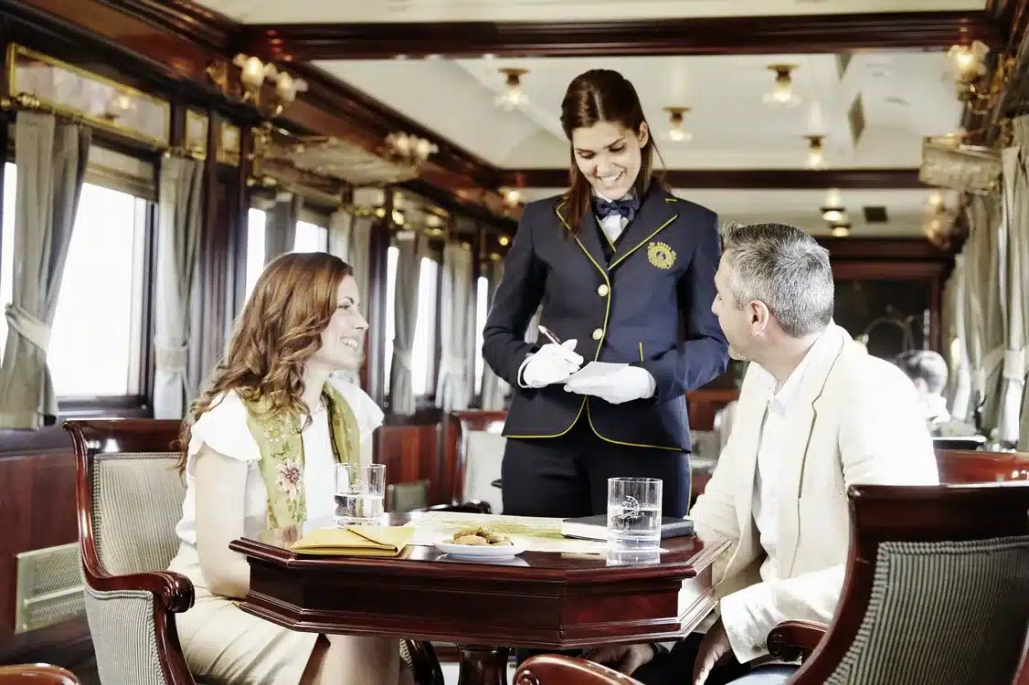Service &agrave; table dans une voiture-restaurant du train Al Andalus avec serveuse en uniforme et clients