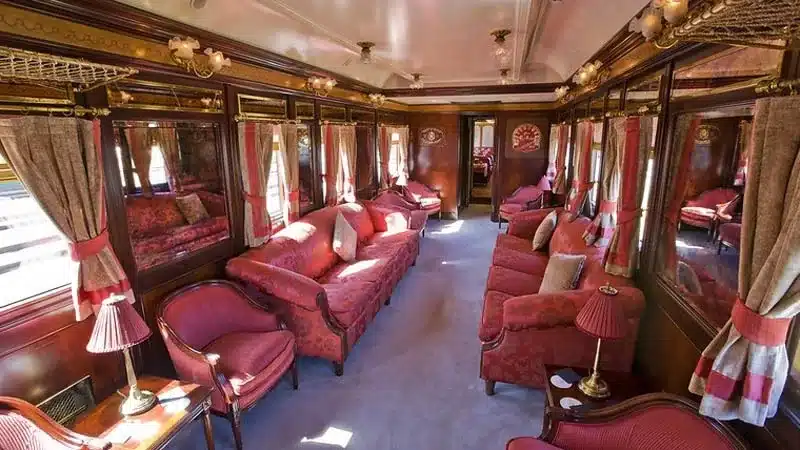 Voiture-salon du train Al Andalus avec canap&eacute;s damass&eacute;s rouges et boiseries marquet&eacute;es d'origine 1928