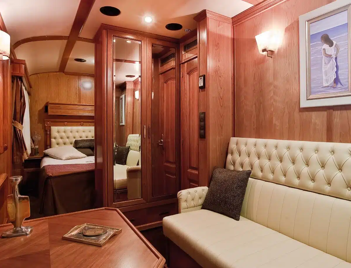 Cabine Suite Deluxe du train Transcant&aacute;brico Gran Lujo avec boiseries acajou, lit double et sofa en cuir capitonn&eacute;