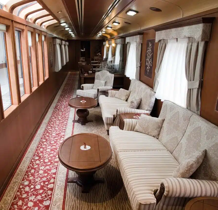 Voiture-salon du train Transcant&aacute;brico Gran Lujo avec sofas cr&egrave;me ray&eacute;s et tapis &agrave; motifs persans