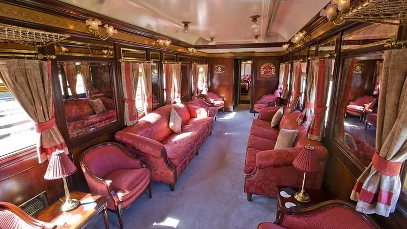 Voiture-salon du train Al Andalus avec canap&eacute;s damass&eacute;s rouges et boiseries marquet&eacute;es